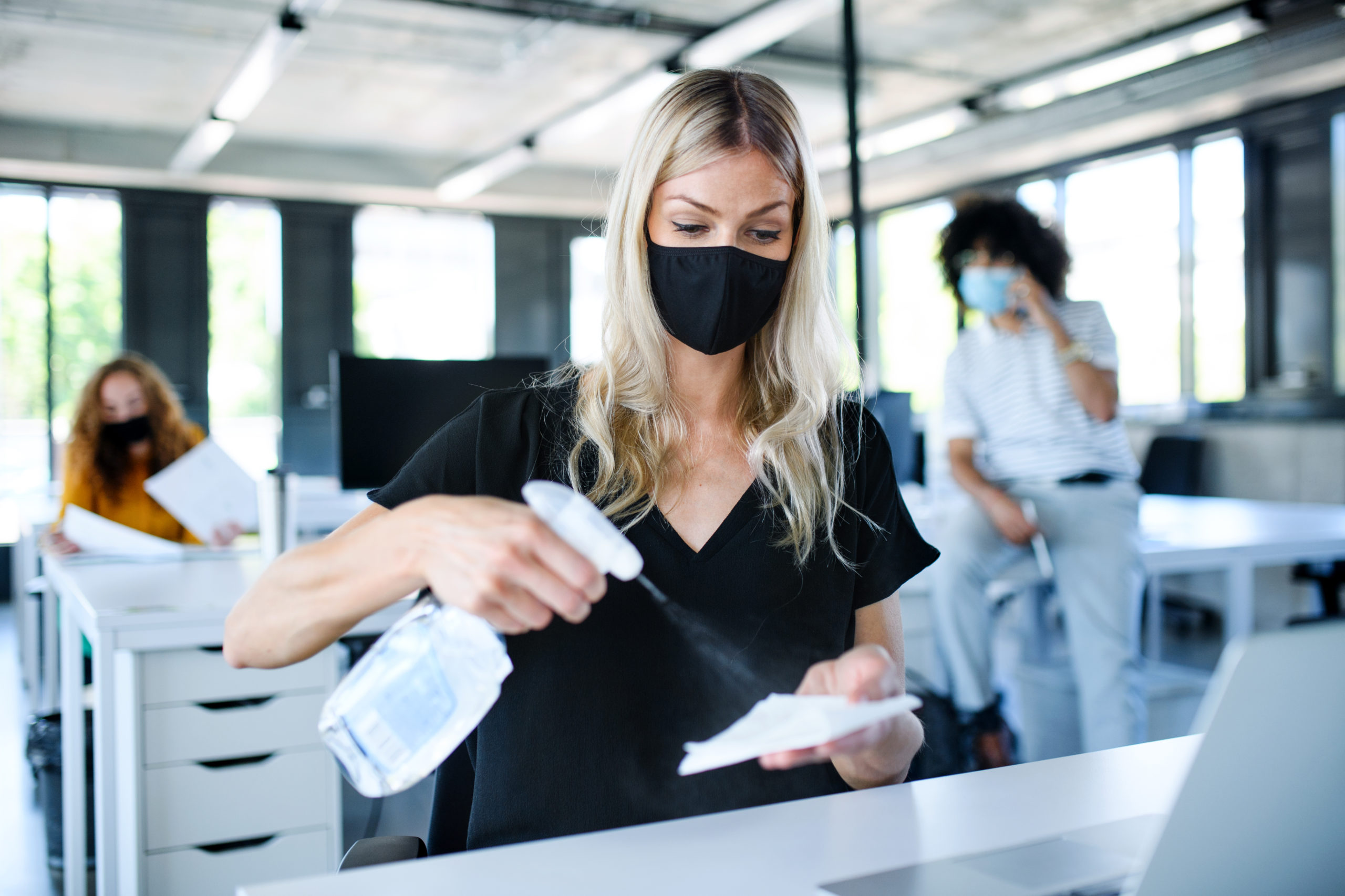 Young woman with face mask back at work in office